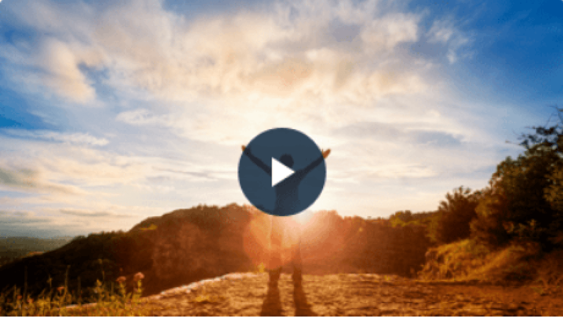 Person with open arms on a hilltop at sunset
