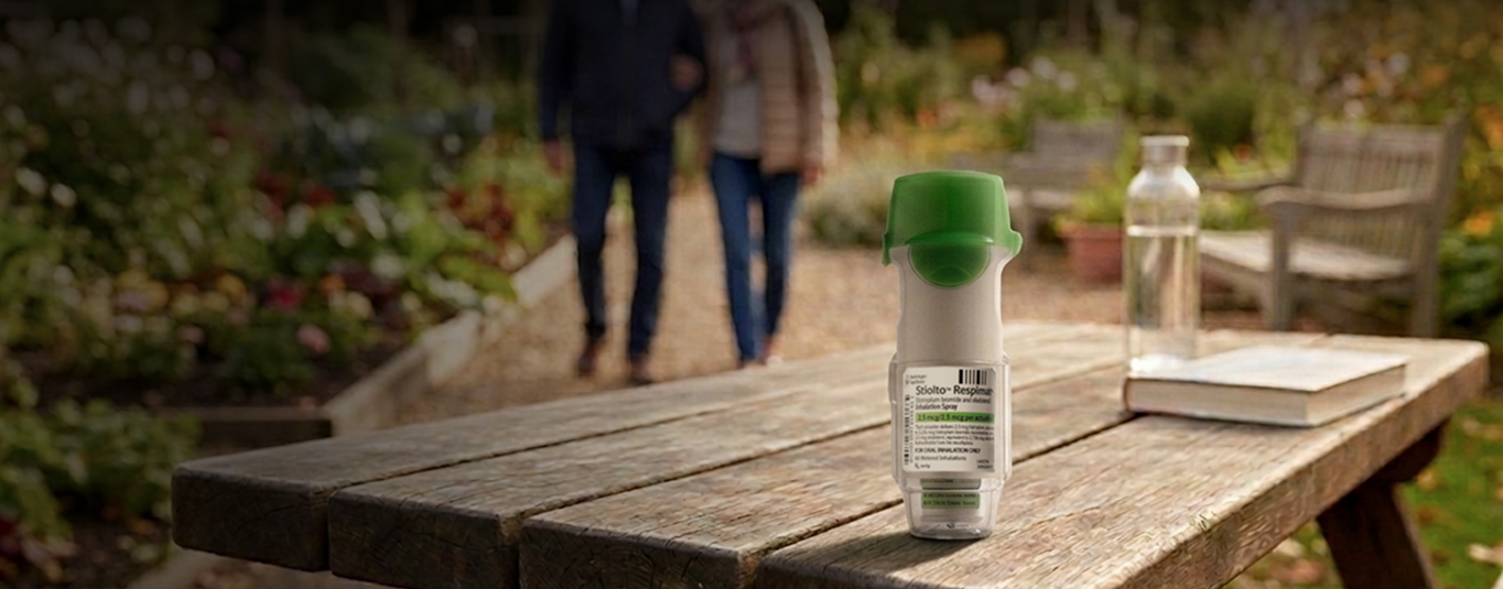 A Stiolto Respimat inhaler standing on a wooden table outdoors