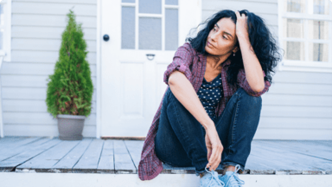 A woman sitting on the porch steps outside a house.